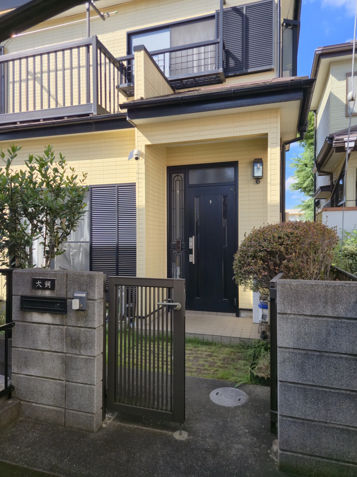 黄色い外壁と黒い玄関ドアの建物・入口